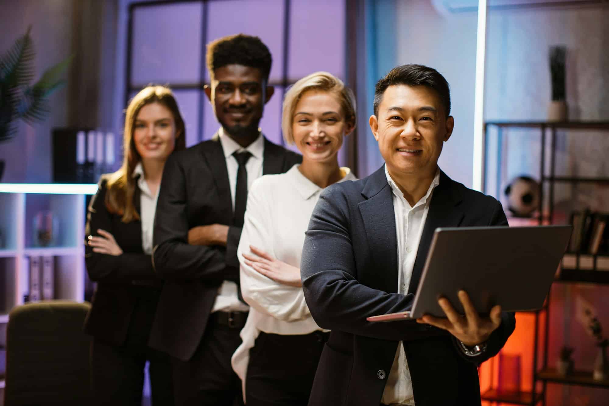 multiethnic happy company workers standing in a row in creative office posing on camera